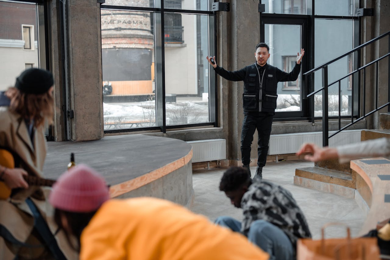 People congregate in a contemporary indoor amphitheater, with a person seeming to guide or perform.